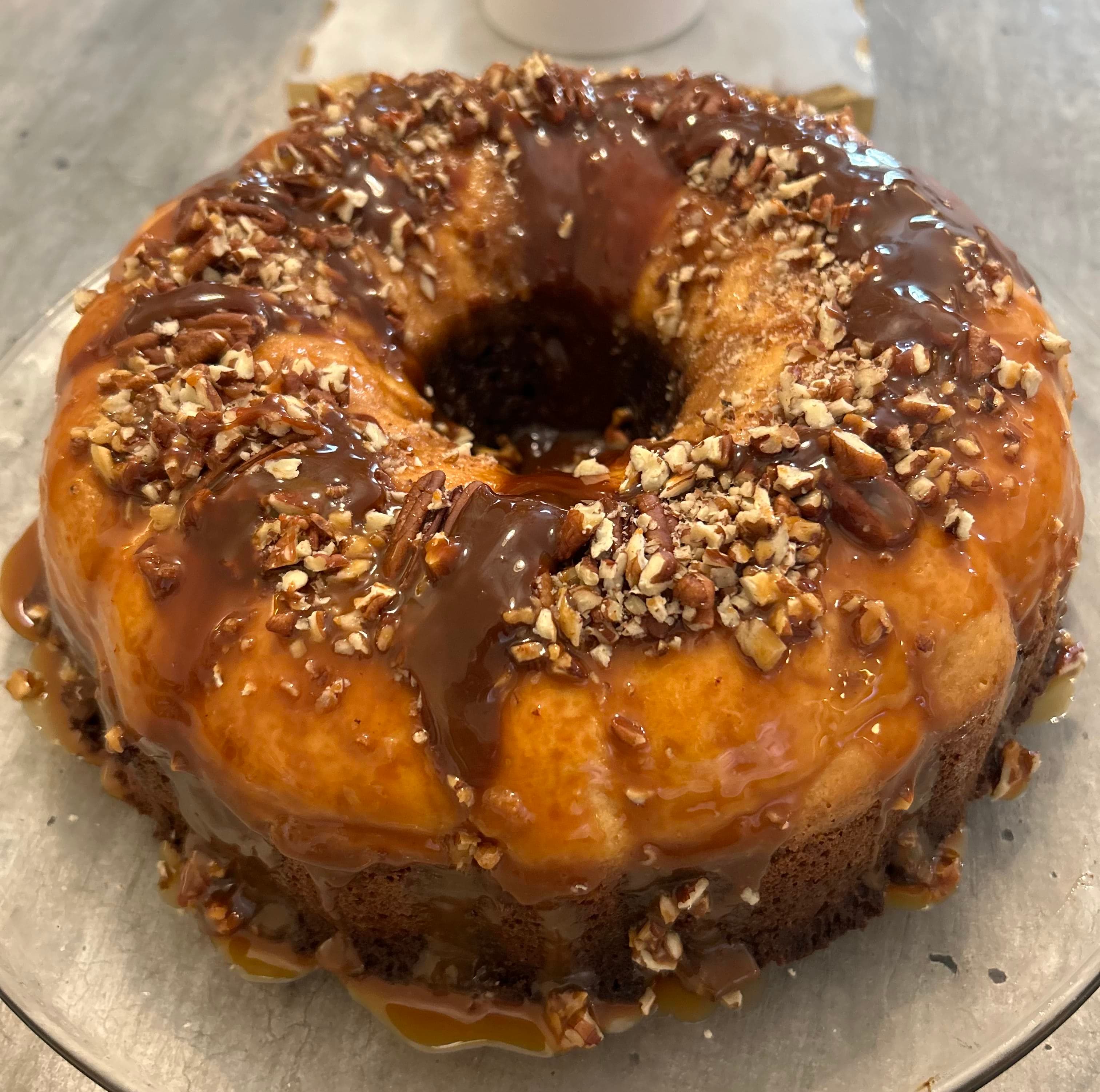 A whole chocoflan drizzled with caramel and topped with chopped pecans